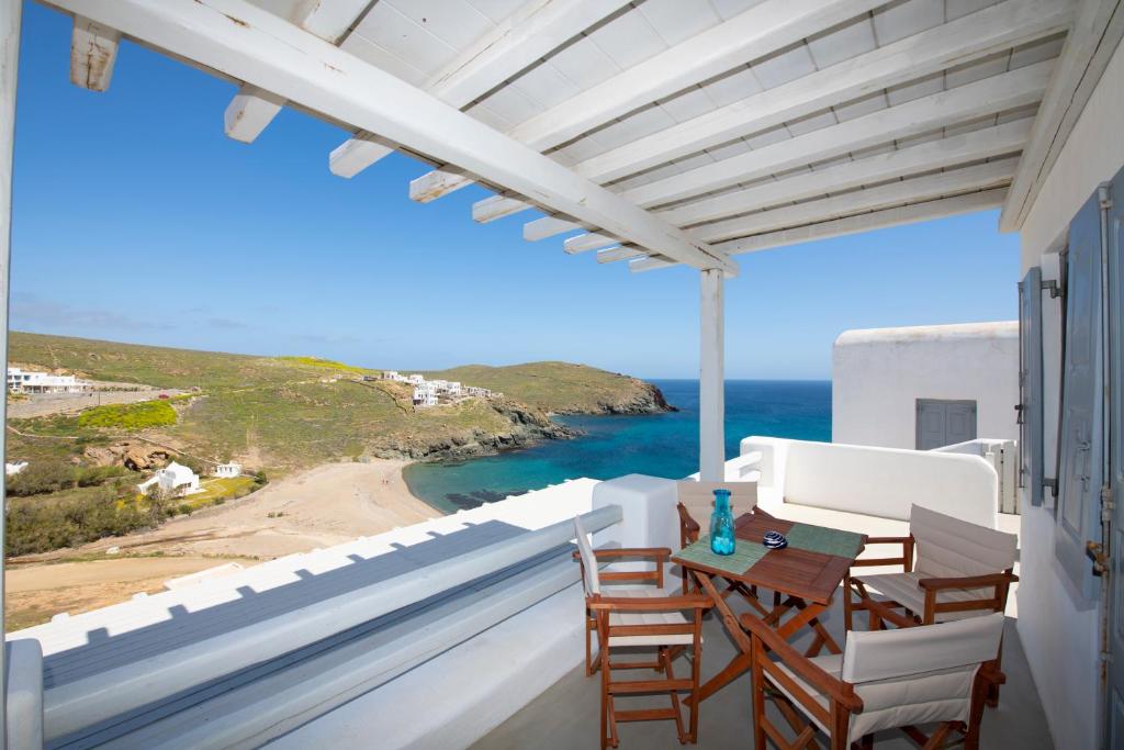 einen Balkon mit einem Tisch, Stühlen und Meerblick in der Unterkunft Superior Beachfront Apartment 1 with view to the Aegean Sea in Panormos, Mykonos