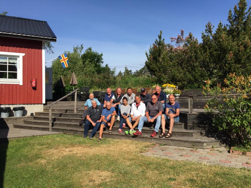 un groupe de personnes assises sur les marches d'une maison dans l'établissement Kastelholms Gästhem, à Sund