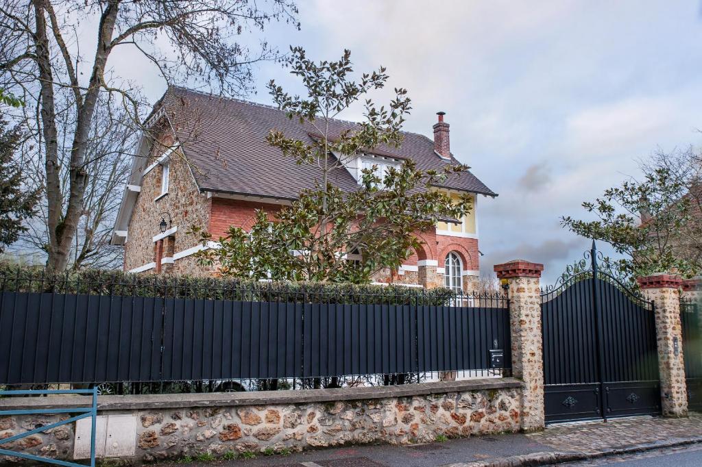 a red brick house with a black fence at Chambre chez l'habitant in Orsay