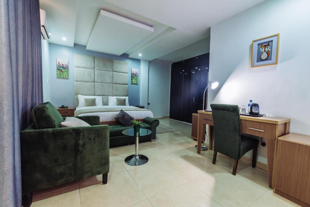 アブジャにあるTranquil Mews Hotelのベッド、デスク、椅子が備わるホテルルームです。