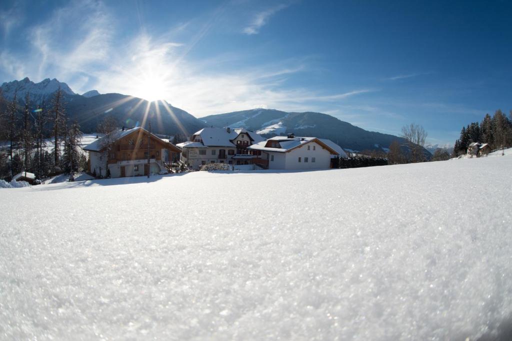 een besneeuwde heuvel met een huis op de achtergrond bij Historic Hotel Alte Goste in Valdaora