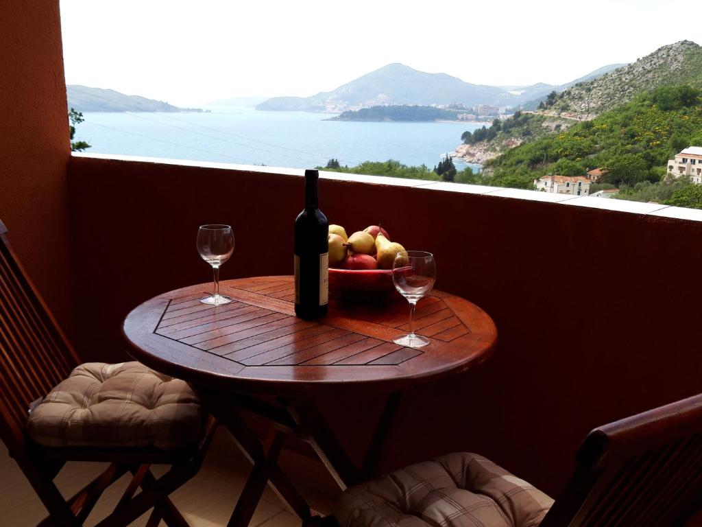 a table with a bowl of fruit and a bottle of wine at Apartments Danilo Kažanegra in Sveti Stefan
