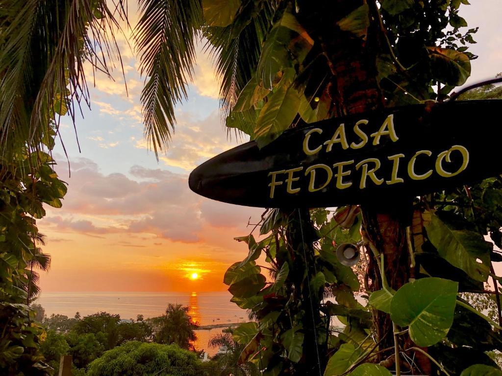 een bord op een boom met een zonsondergang op de achtergrond bij Casa Federico in Quepos