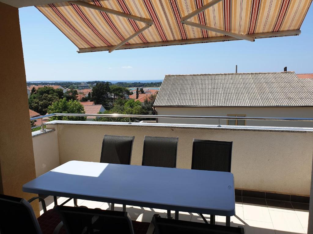 a blue table and chairs on a balcony at Apartment FERAL Novalja in Novalja