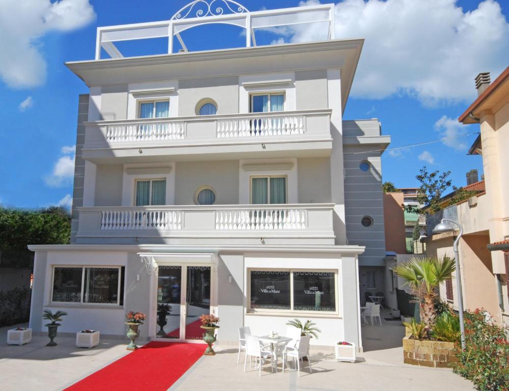 un edificio blanco con balcón y alfombra roja en Hotel Residence Villa Del Mare, en Rímini