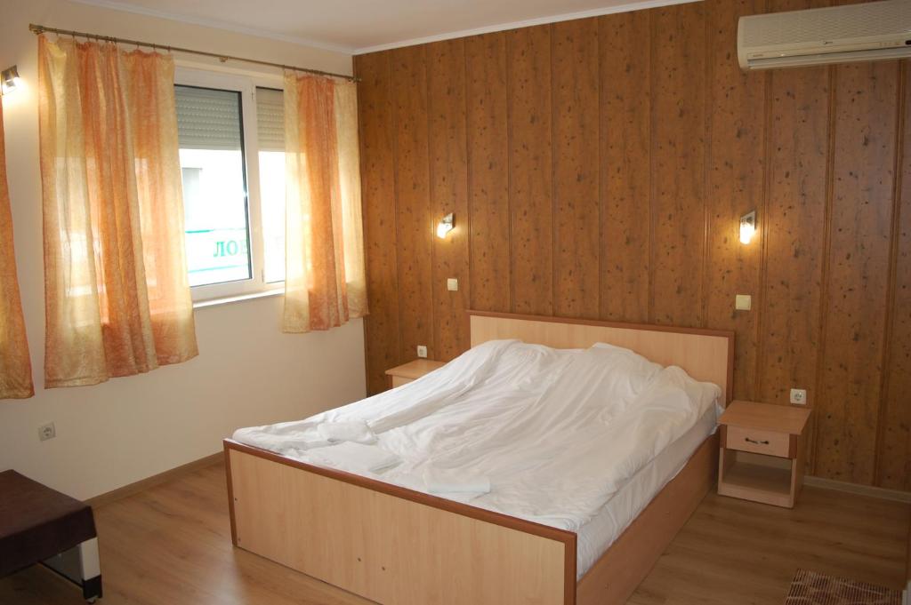 a bedroom with a bed with white sheets and a window at Hotel Vitosha in Tryavna