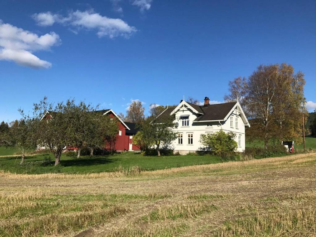 een wit huis op een veld met een rood huis bij Nedre Eie in Lunde