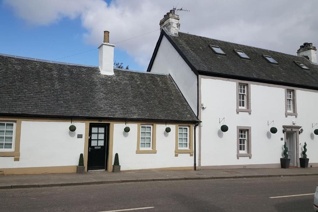 a white building with a black roof on a street at Thornhill Lodge, Historic 4 Bed, 4 Ensuite in Stirling