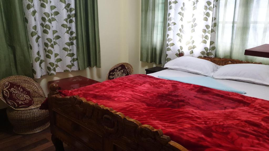 a bedroom with a bed with a red blanket on it at Mahakal homestay in Darjeeling