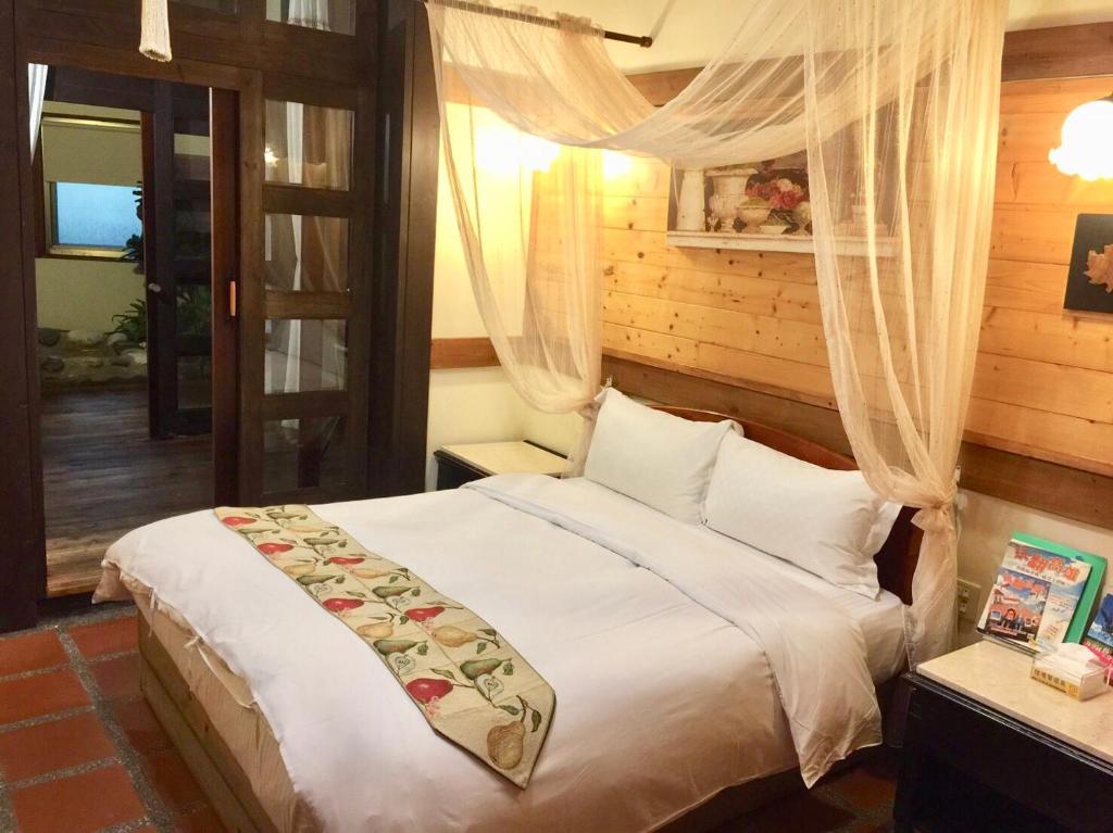 a bedroom with a bed with white sheets and curtains at New Life Hot Spring Resort in Yuli