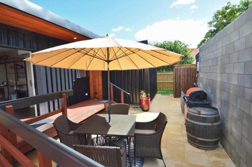 a patio with a table with an umbrella and a barrel at BeachBox Boutique Accommodation in Coopers Beach