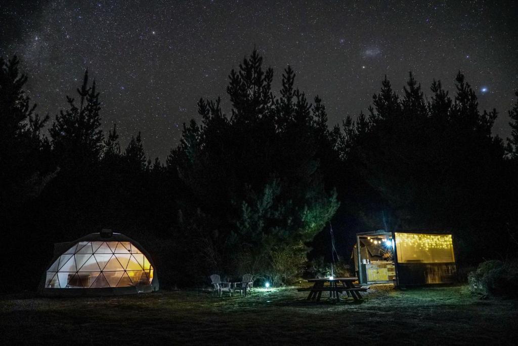 a tent and a table in a field at night at Mt Gold Glamping in Wanaka