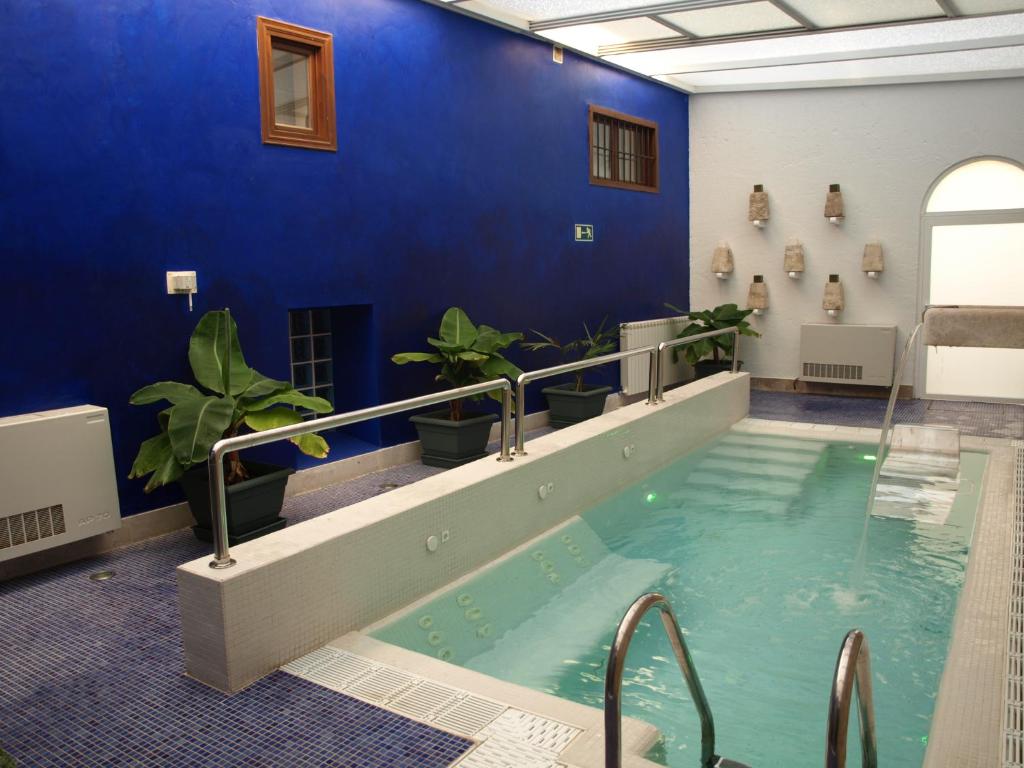 una gran piscina cubierta con una pared azul y plantas en Hotel Spa La Casa Del Convento, en Chinchón