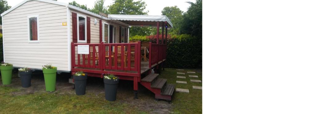 a tiny house with a red porch and stairs at Mobile home dans les Landes in Gastes