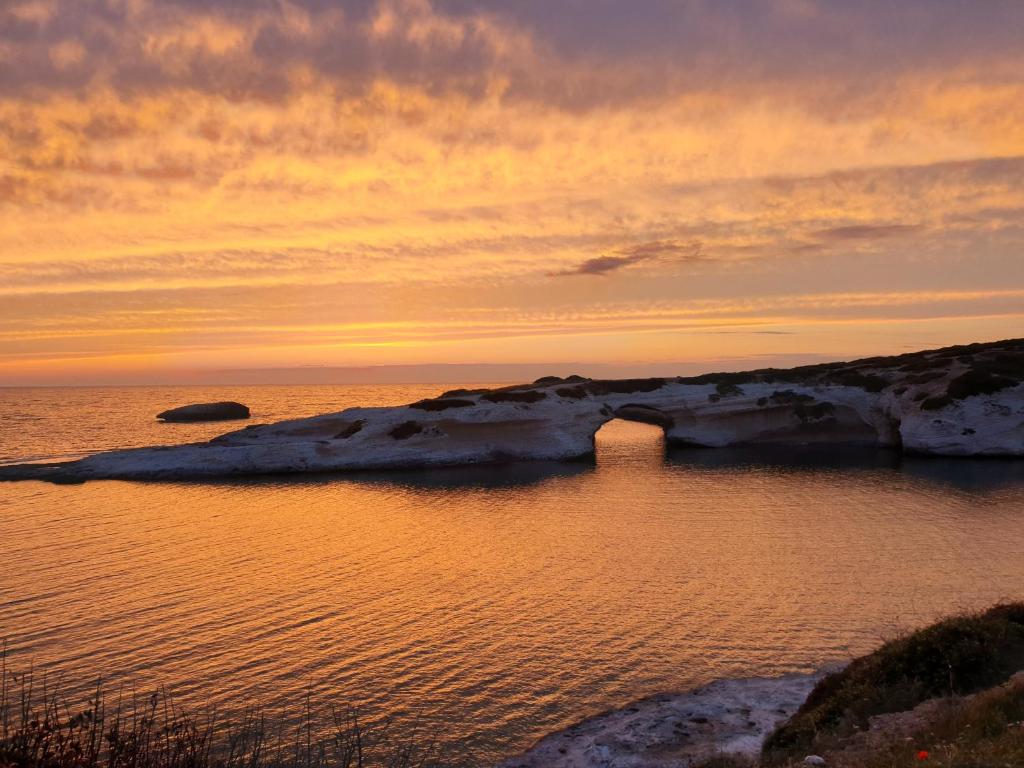 un tramonto su un corpo d'acqua con rocce di Mare Lughente a S'archittu Cuglieri