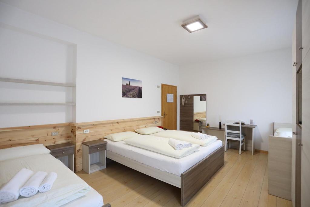 a large room with two beds and a desk at Albergo Bellaria in Carano