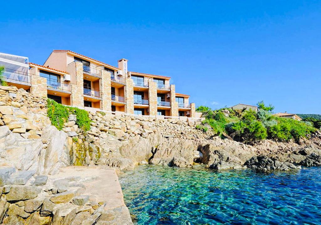 ein Gebäude auf einer Klippe neben dem Wasser in der Unterkunft Hôtel du Golfe in Sartène