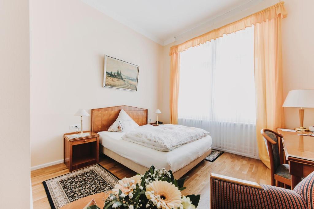 a bedroom with a bed and a desk and a window at Hotel Spöttel in Bad Nauheim