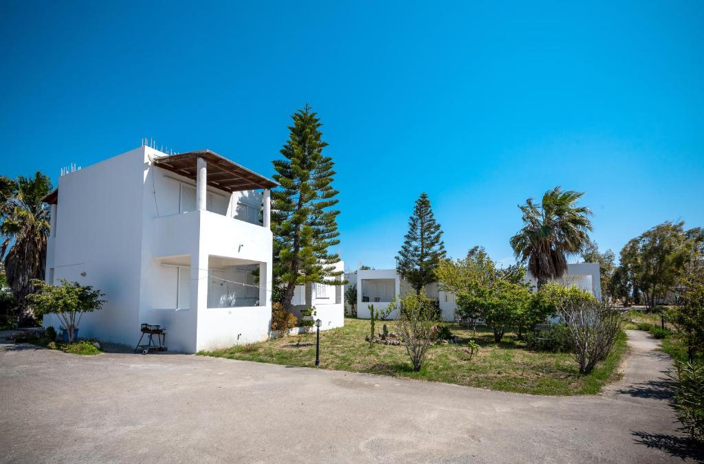una casa blanca con palmeras delante en Fotini Studios, en Kámpos