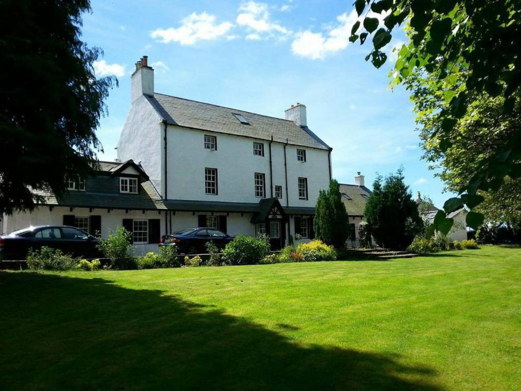 a large white house with a green lawn at Stuc an t Sagairt Cottage , Loch Lomond in Drymen