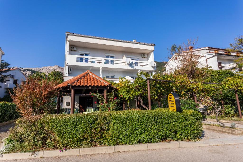 un edificio bianco con un cartello davanti di Apartmani Velnic a Baška