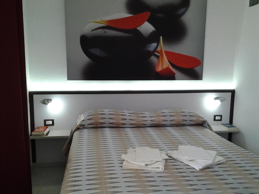 a bedroom with a bed with two tables and a painting at La Rosa Affittacamere in La Caletta