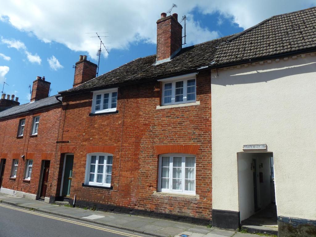 uma casa de tijolos vermelhos ao lado de uma rua em The Little House em Devizes