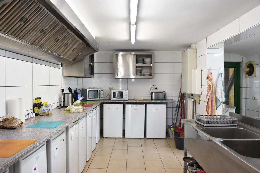 a large kitchen with white cabinets and appliances at Kutscherhof Broock in Broock