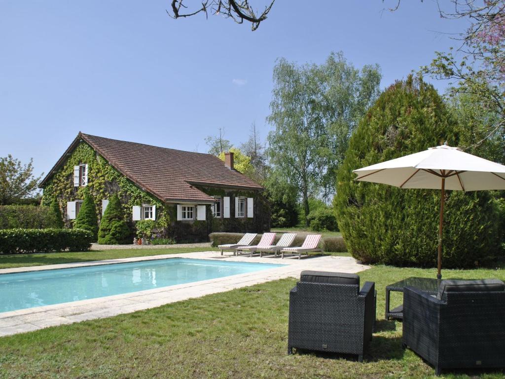 a pool with an umbrella and chairs and a house at Mansion in Charrin by Loire with Pool in Charrin