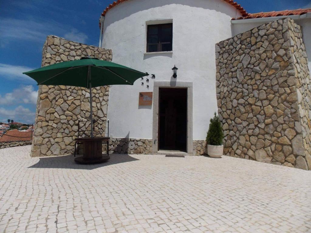 un edificio con una sombrilla verde delante de él en Casa Moinho do Oeste - West Windmill Portugal, en Moledo