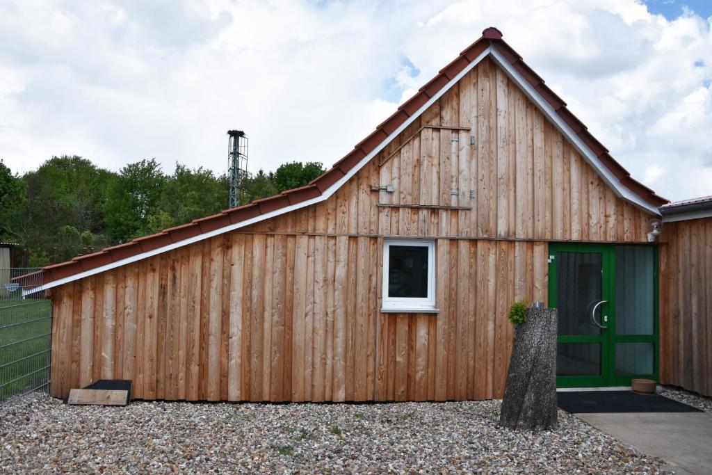 a large wooden barn with a green door at Kutscherhof Broock in Broock