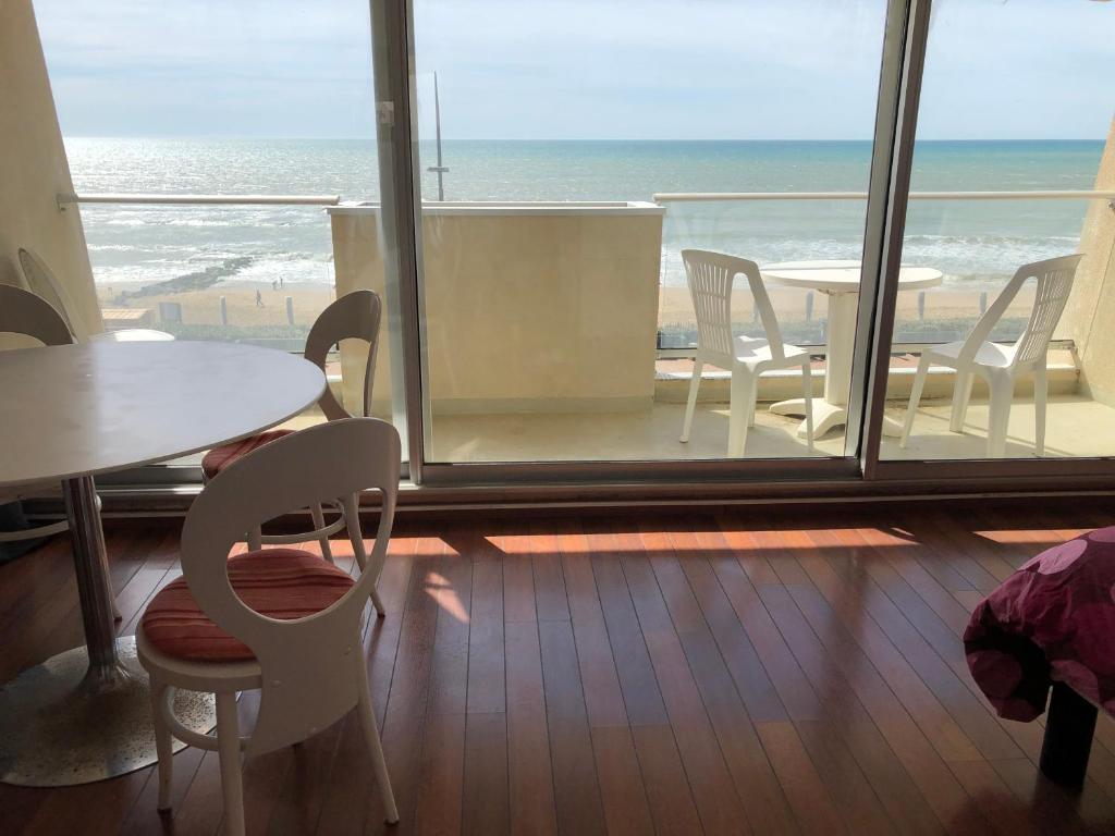een kamer met een tafel en stoelen en uitzicht op de oceaan bij Studio Face Ocean in Lacanau