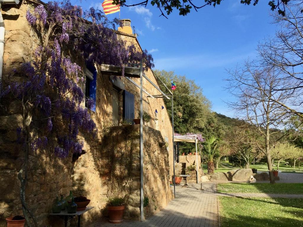 un edificio con flores púrpuras a su lado en Can Guilló 1, en Darnius