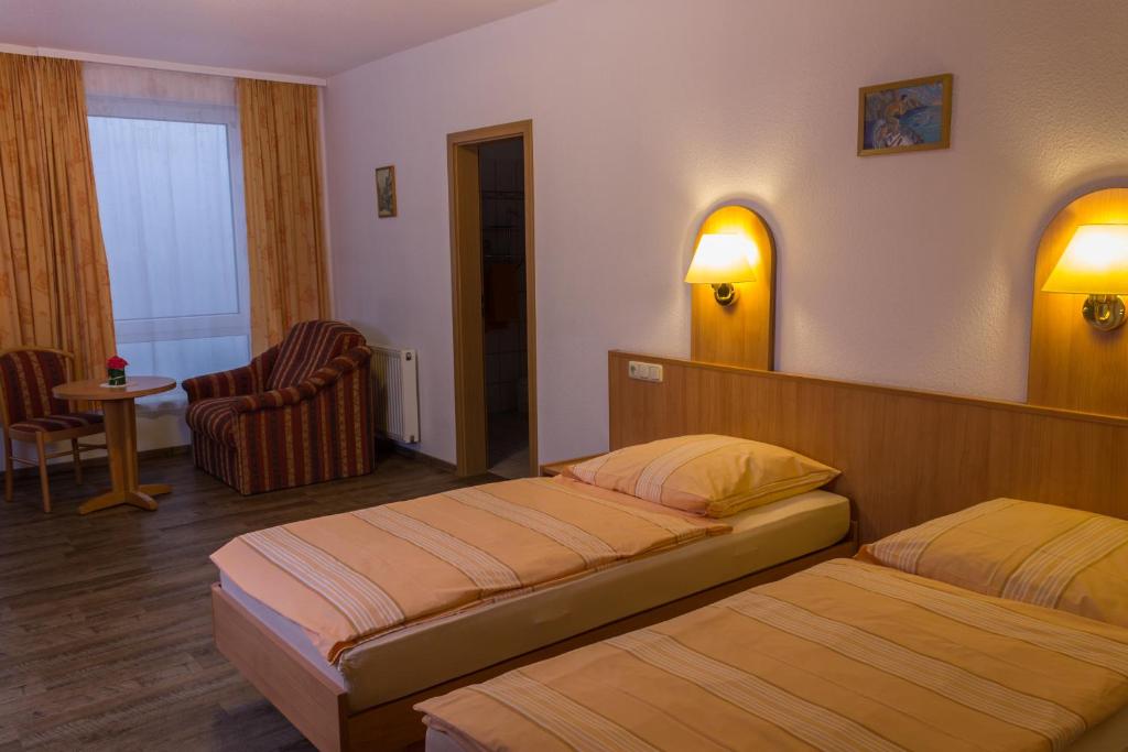 a hotel room with two beds and a chair at TOTO's Gasthaus in Hattingen