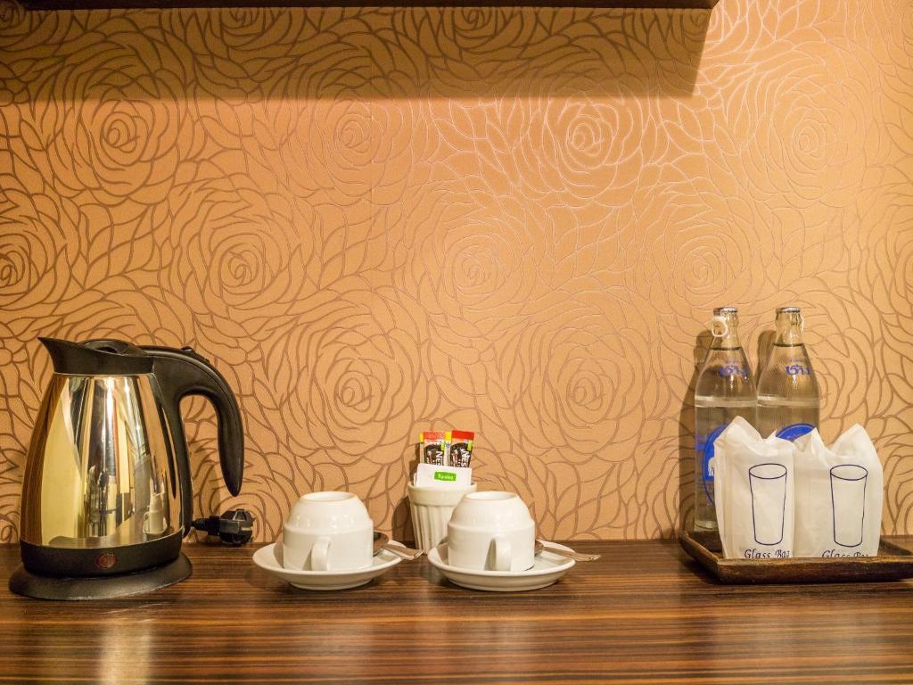 An in-room beverage station with an electric kettle, cups, bottled water, and drink supplies.