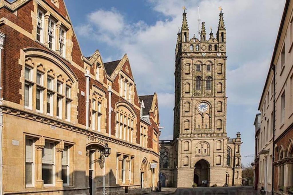 ein Gebäude mit einem Uhrturm und einer Kirche in der Unterkunft Warwick Post Office Apartment in Warwick