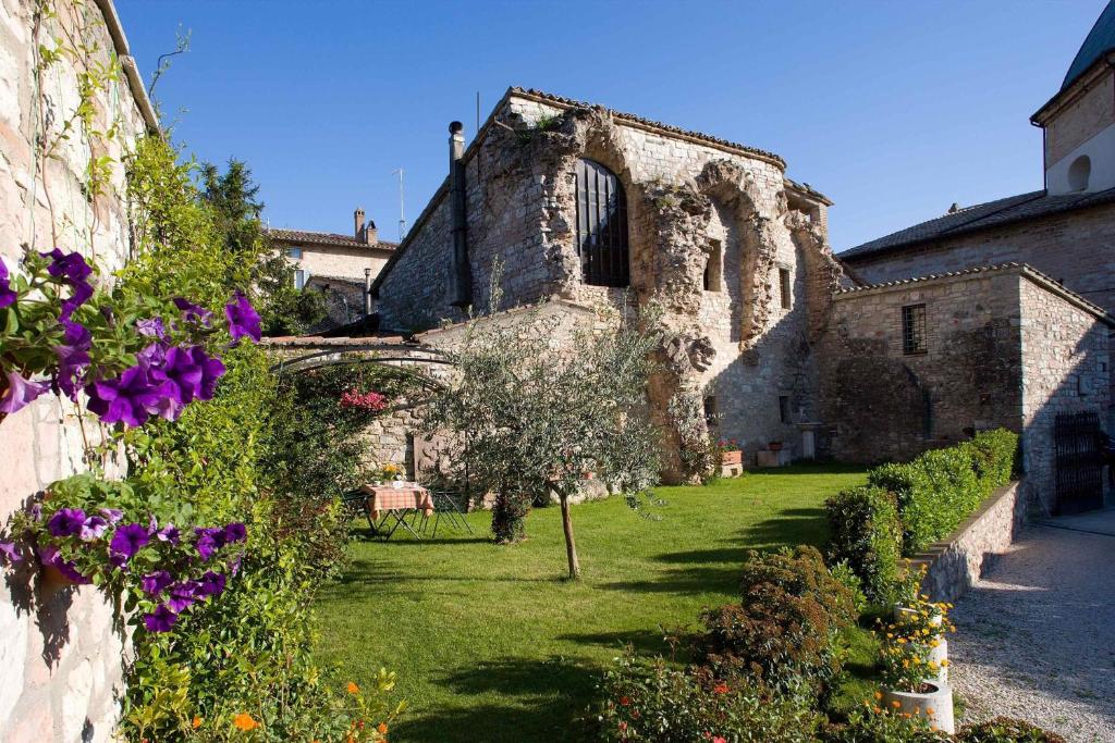 un antiguo edificio de piedra con flores en el patio en Il Turrione, en Asís