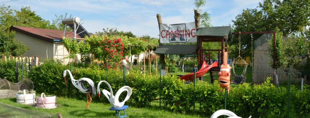 une cour avec une aire de jeux ornée de sculptures de cygne dans l'herbe dans l'établissement Camping Casuta Mihaela, à Crisan