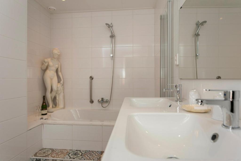 een witte badkamer met een wastafel en een bad bij Het Vakwerkhuis in Valkenburg