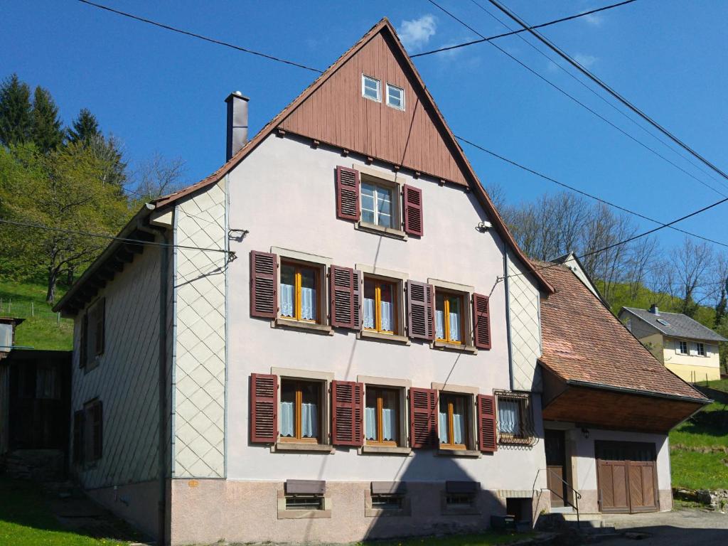 ein großes weißes Haus mit braunen Fensterläden in der Unterkunft Le Chamois in Sondernach