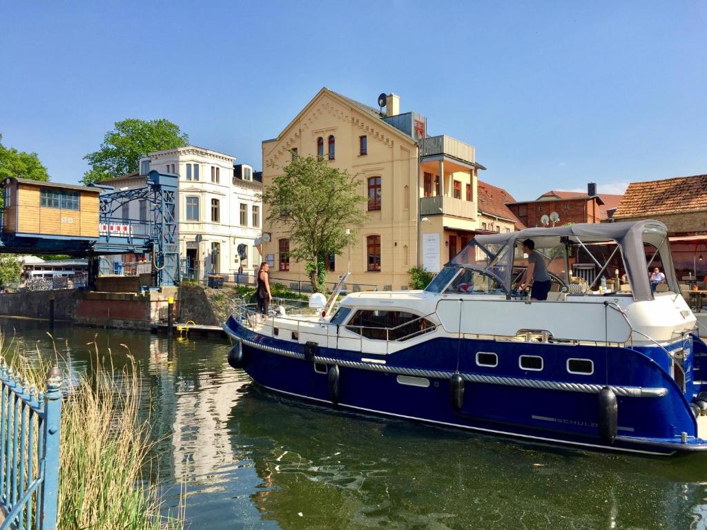 ein blaues und weißes Boot in einem Fluss mit Gebäuden in der Unterkunft Venedig und Amsterdam in Plau am See