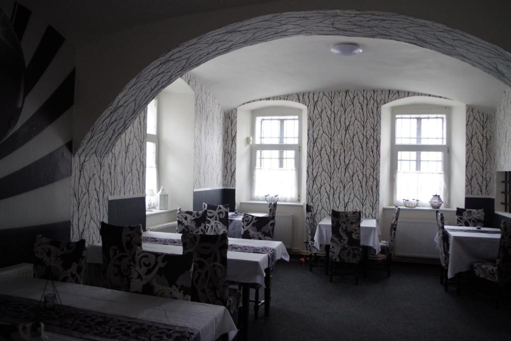 ein Zimmer mit Tischen und Stühlen und zwei Fenstern in der Unterkunft Penzion U Soudu in Hora Svatého Šebestiána