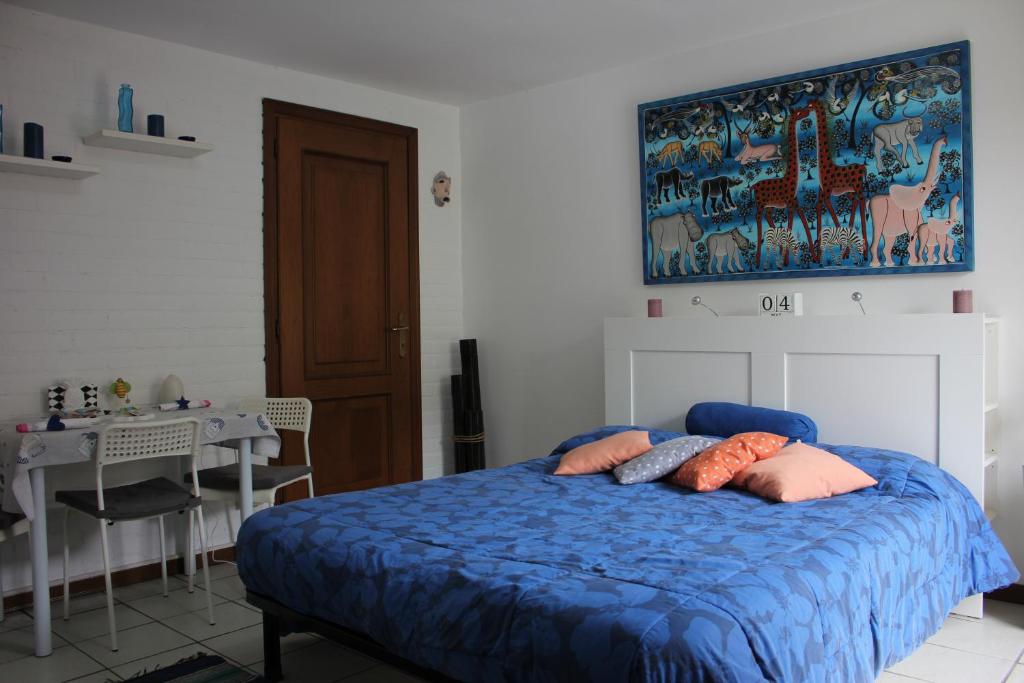 a bedroom with a blue bed with pillows and a table at Alimat Apartment in Lignano Sabbiadoro