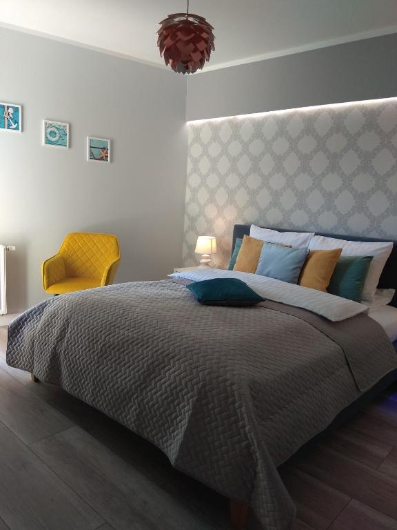 a bedroom with a large bed and a yellow chair at Apartament Cesarski Agnes- bezpłatny parking- Resort Cesarskie Ogrody in Świnoujście