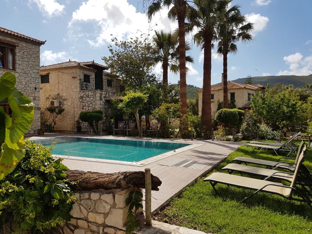 a swimming pool with two chairs and a house at Castello Bellos Villas & Apartments in Keri