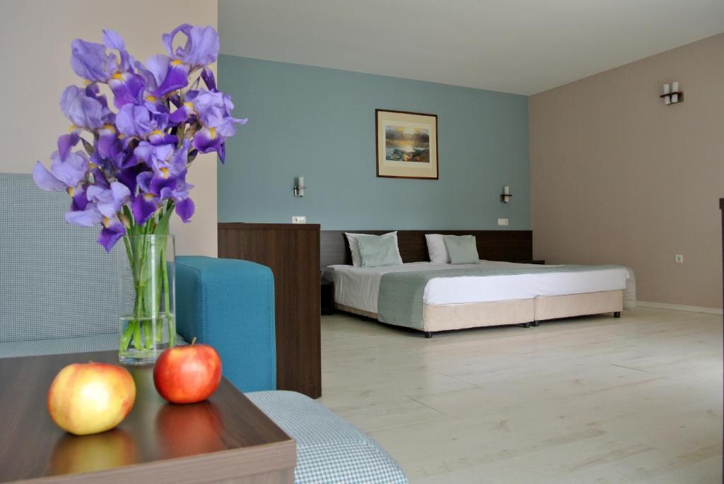 Valeo Hotel في بالشيك: غرفة نوم مع سرير و مزهرية من الزهور الأرجوانية