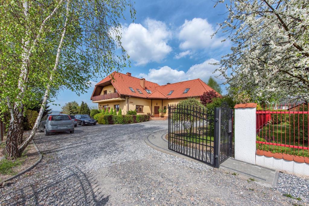 a house with a gate in front of a driveway at RYSIÓWKA pokoje gościnne in Modlniczka