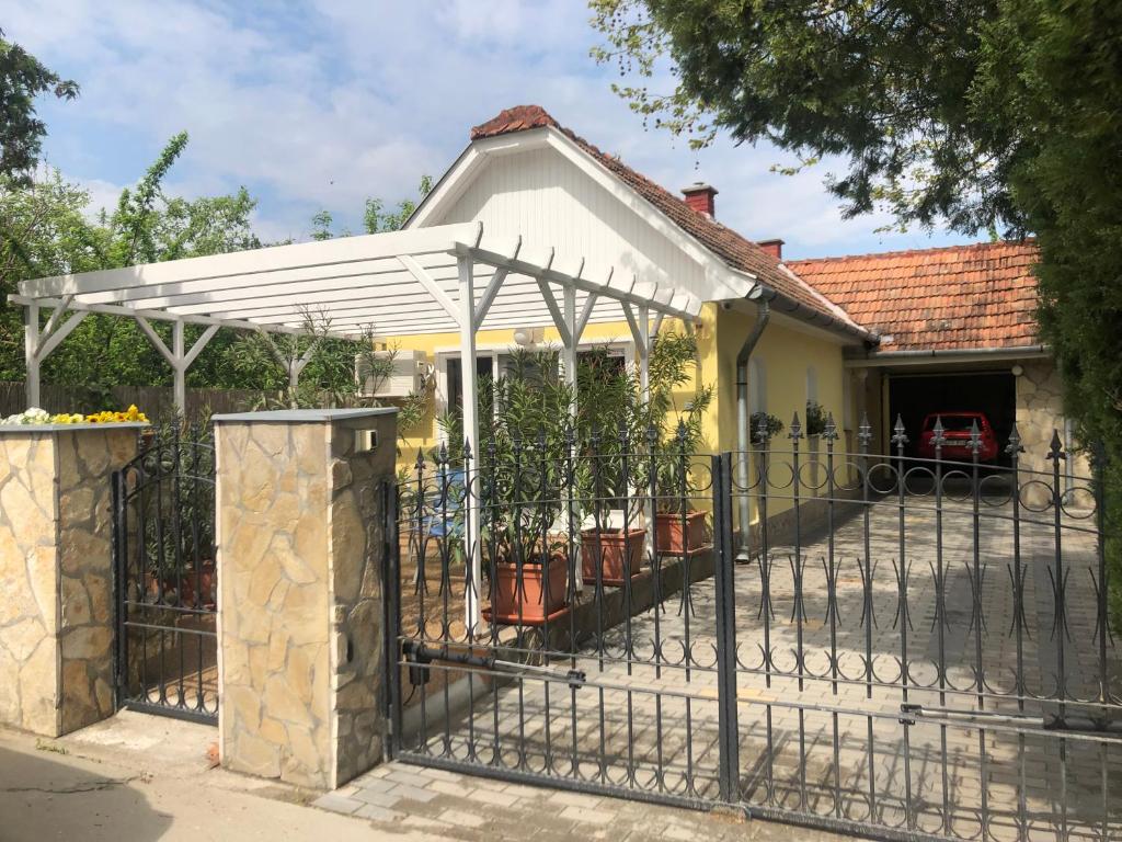 a fence in front of a house with a white canopy at Thermal Garden Weninger Apartmanok in Kiskunhalas