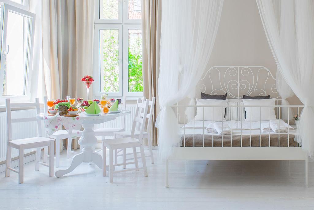a white bedroom with a bed and a table with chairs at Riviera Residence Apartments in Sopot
