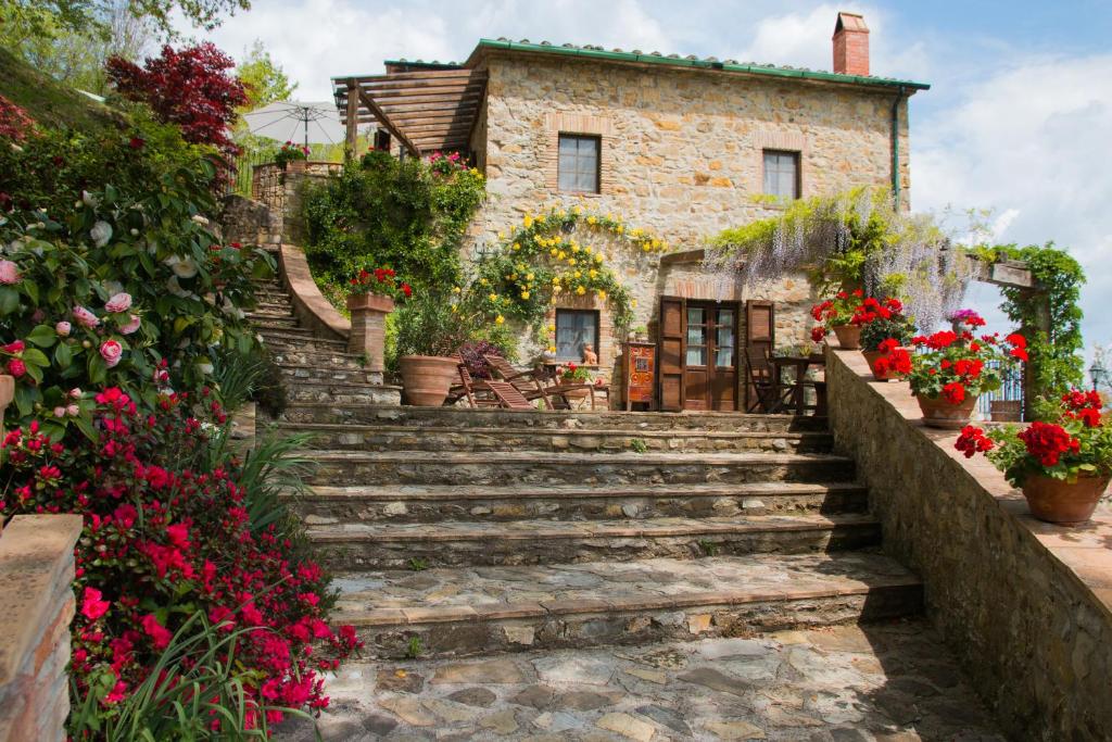 una antigua casa de piedra con escaleras y flores en Podere Piandicava, en Castelnuovo di Val di Cecina